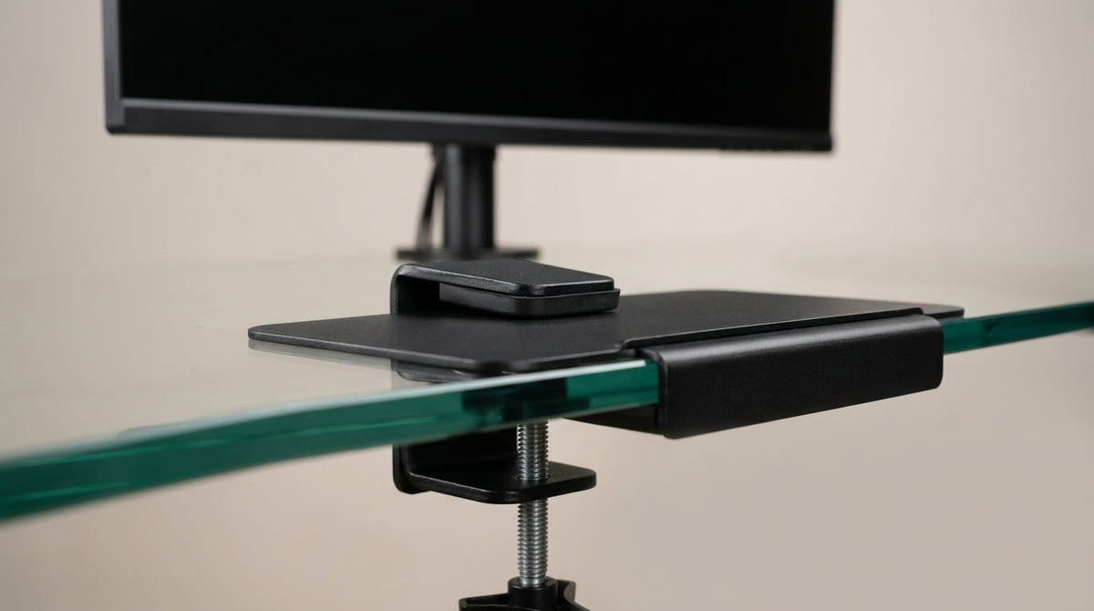 Close-up of monitor arm clamp with reinforcement plate on tempered glass desk edge